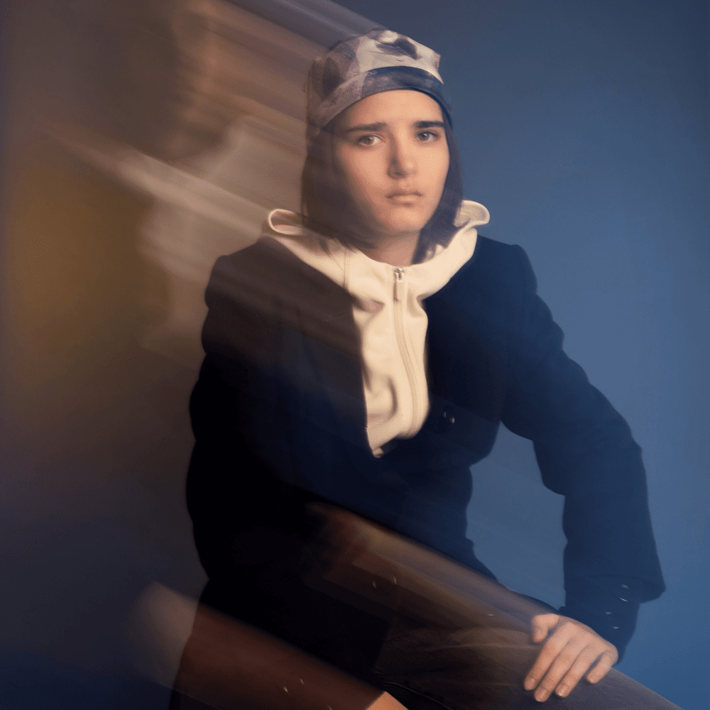 Model wearing the Blue Feathers Beanie, blurred with motion streaks, against a blue and yellow gradient.