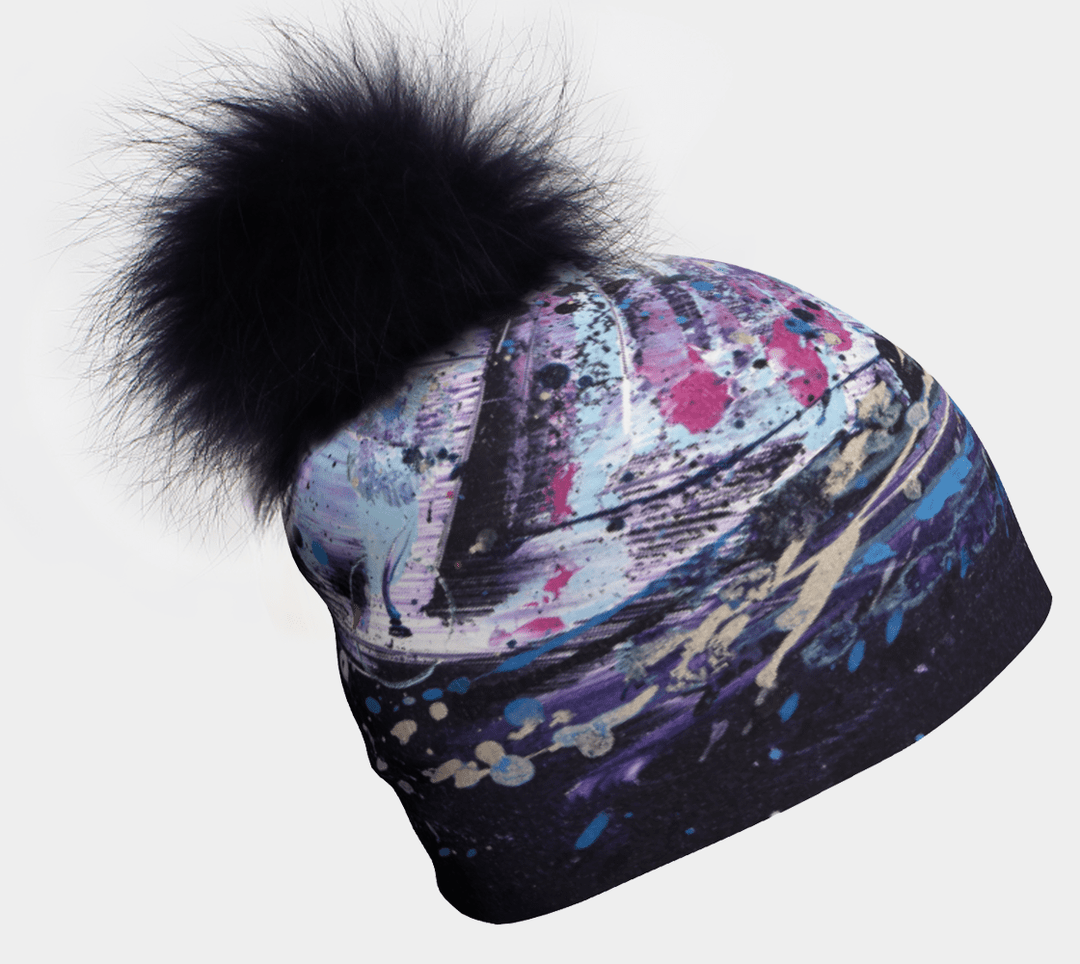 Tuque cosmique avec pompon, motif artistique abstrait et pompon noir duveteux sur fond blanc.