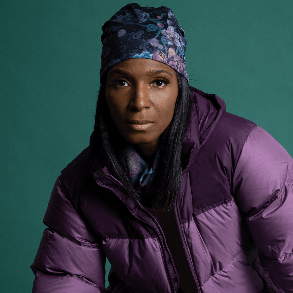 Une femme portant une veste d'hiver violette et une tuque florale, avec le tube assorti visible.