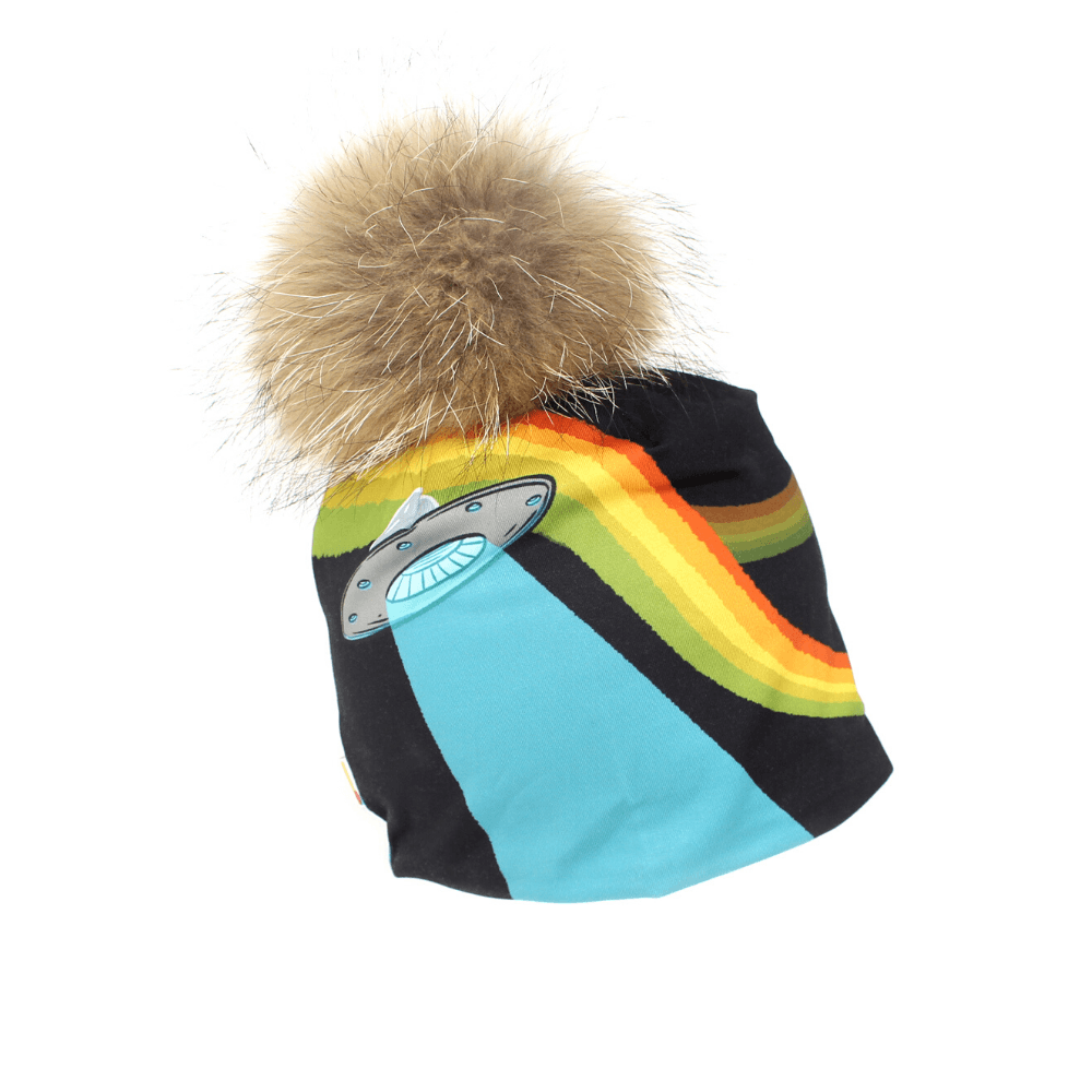 Tuque noire avec une bande arc-en-ciel colorée et une application de soucoupe volante, surmontée d'un grand pompon en fourrure brune et moelleuse.