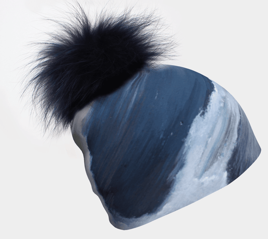Tuque Mer Dorée abstraite peinte en bleu et blanc avec un pompon noir duveteux.