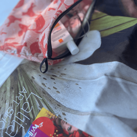 Gros plan de la serviette Guerrière Pacifique et de sa pochette incluse, montrant de la crème solaire et des articles de toilette.