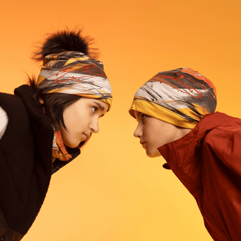 Vue de profil de deux jeunes personnes portant la tuque Le Cœur et des cache-cous.