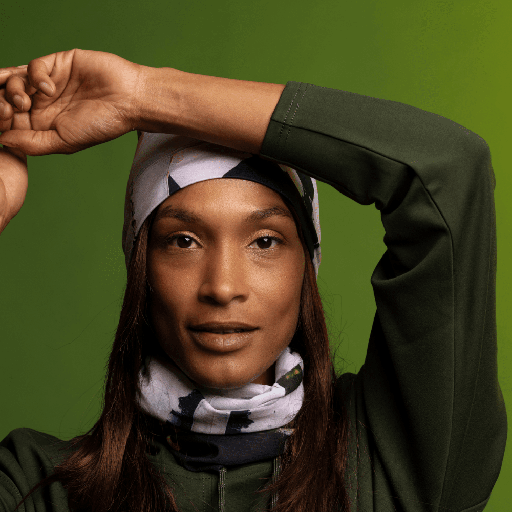 Une femme portant un sweat à capuche et une tuque vert olive assortis, avec le tube multifonctionnel « Modern Quilt » autour du cou.