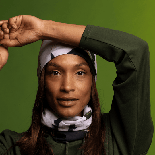 Une femme portant un sweat à capuche et une tuque vert olive assortis, avec le tube multifonctionnel « Modern Quilt » autour du cou.