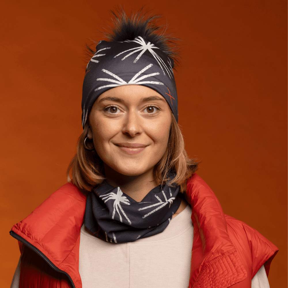 Une femme souriante portant un gilet rouge et une tuque et un tube assortis avec un motif étoile.
