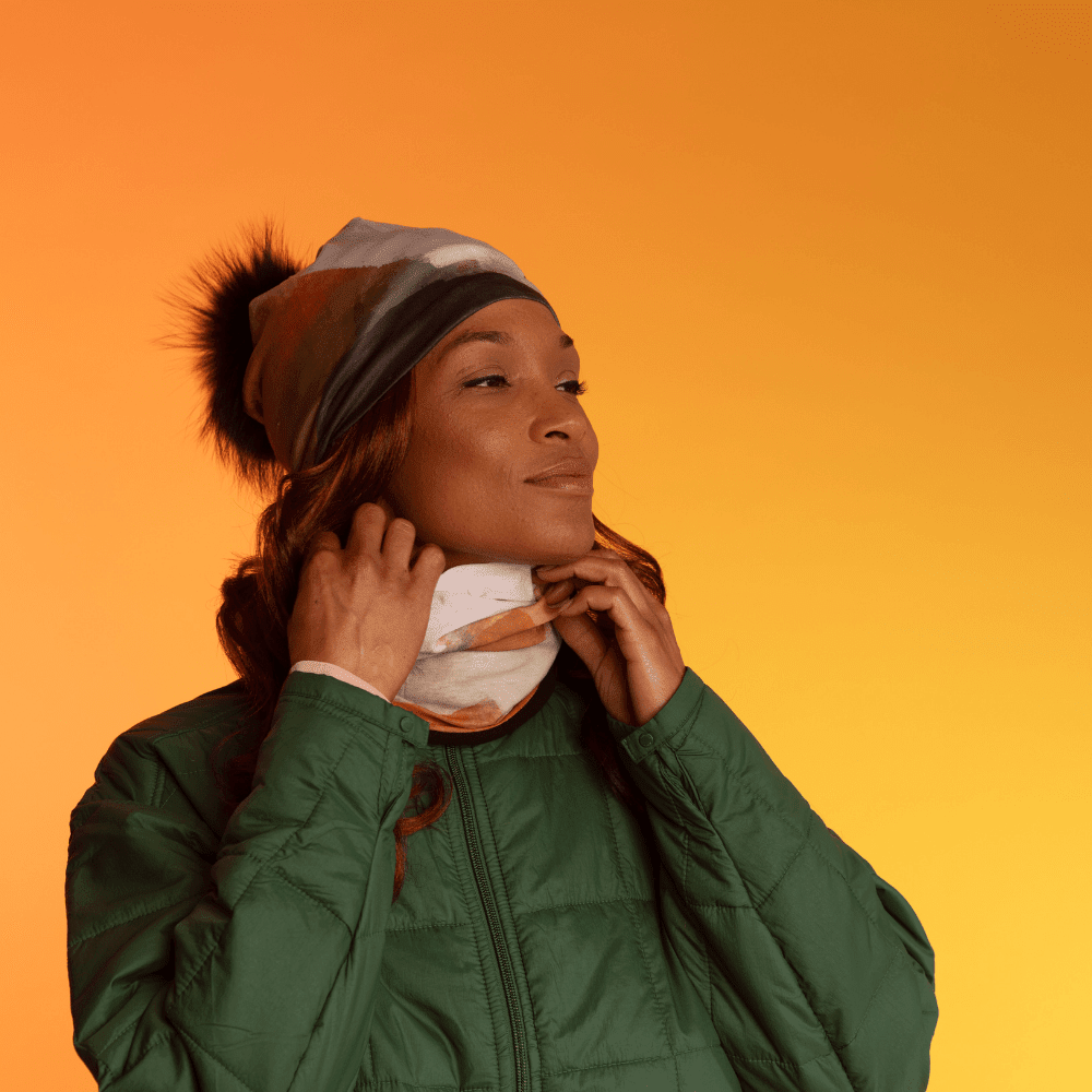 Woman wearing the Navy Accent Beanie With Detachable Pompom and adjusting a neck gaiter.