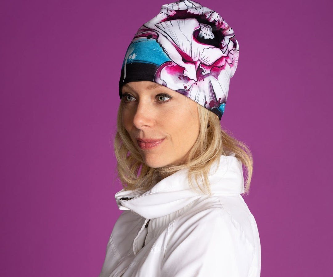 Woman wearing the New Poppy Beanie for Girls and Women, showcasing its artistic floral design against a purple background.