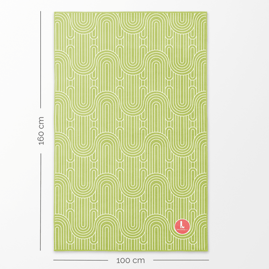 Une grande serviette en microfibre avec un motif géométrique vert exposée à plat avec indication des dimensions de 160 cm de longueur et 100 cm de largeur.