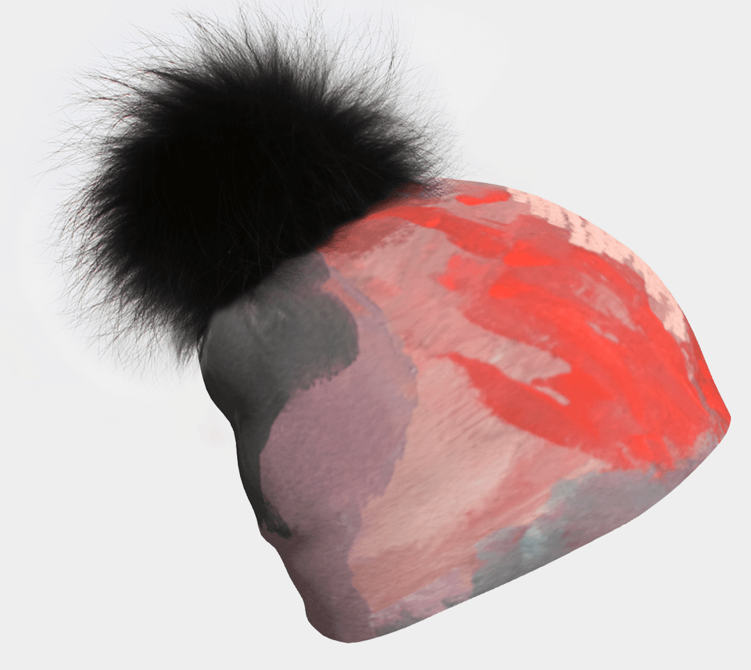 Tuque avec un imprimé abstrait rose et orange et un pompon noir.