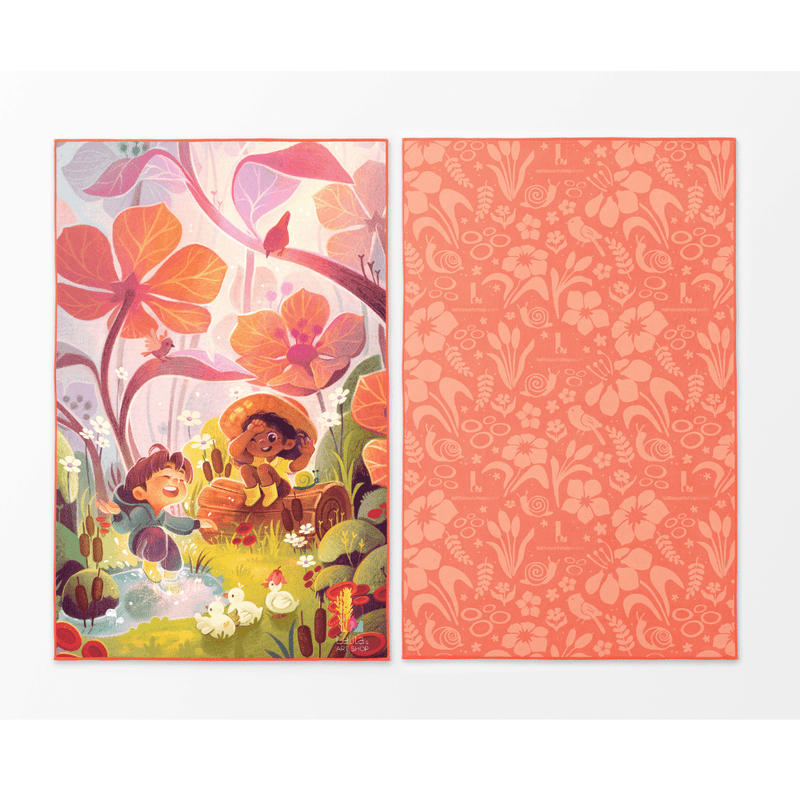 Deux côtés de la serviette pour enfants Pluie Joueuse à plat, le gauche montrant une illustration colorée d'enfants et de canards, le droit montrant un motif floral corail.