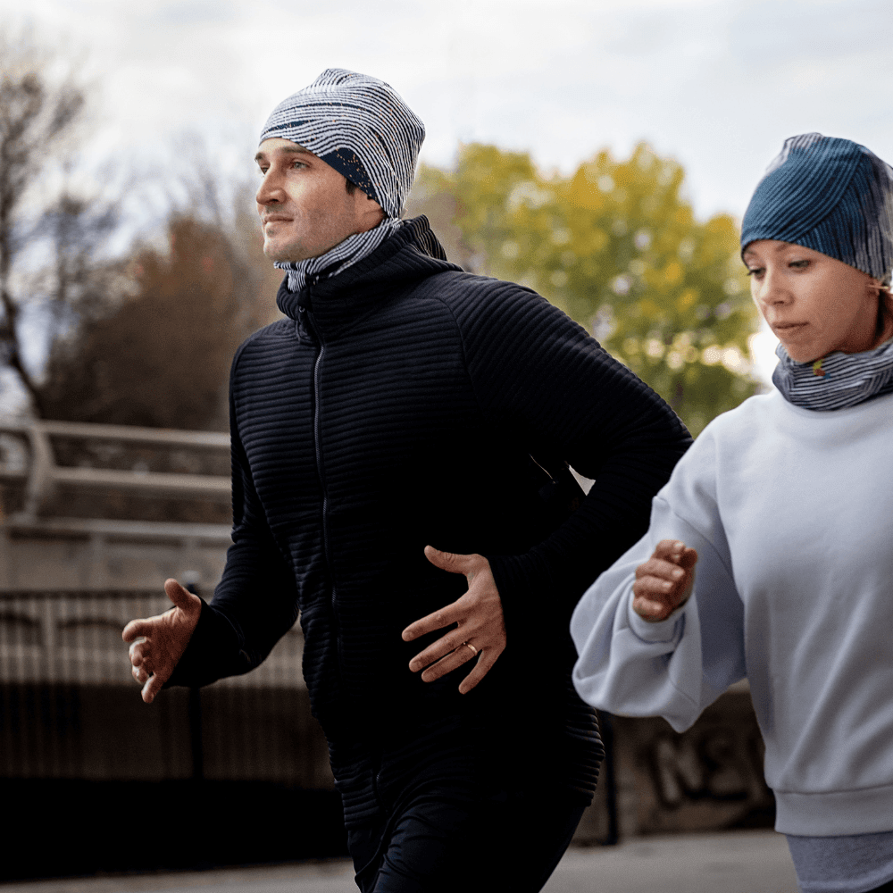 Homme et femme portant des tubes multifonctionnels POLAR Dark Steel assortis en tuques et cache-cous tout en courant à l&