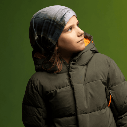 Une jeune personne portant une veste bouffante vert foncé et une tuque ornée de l&