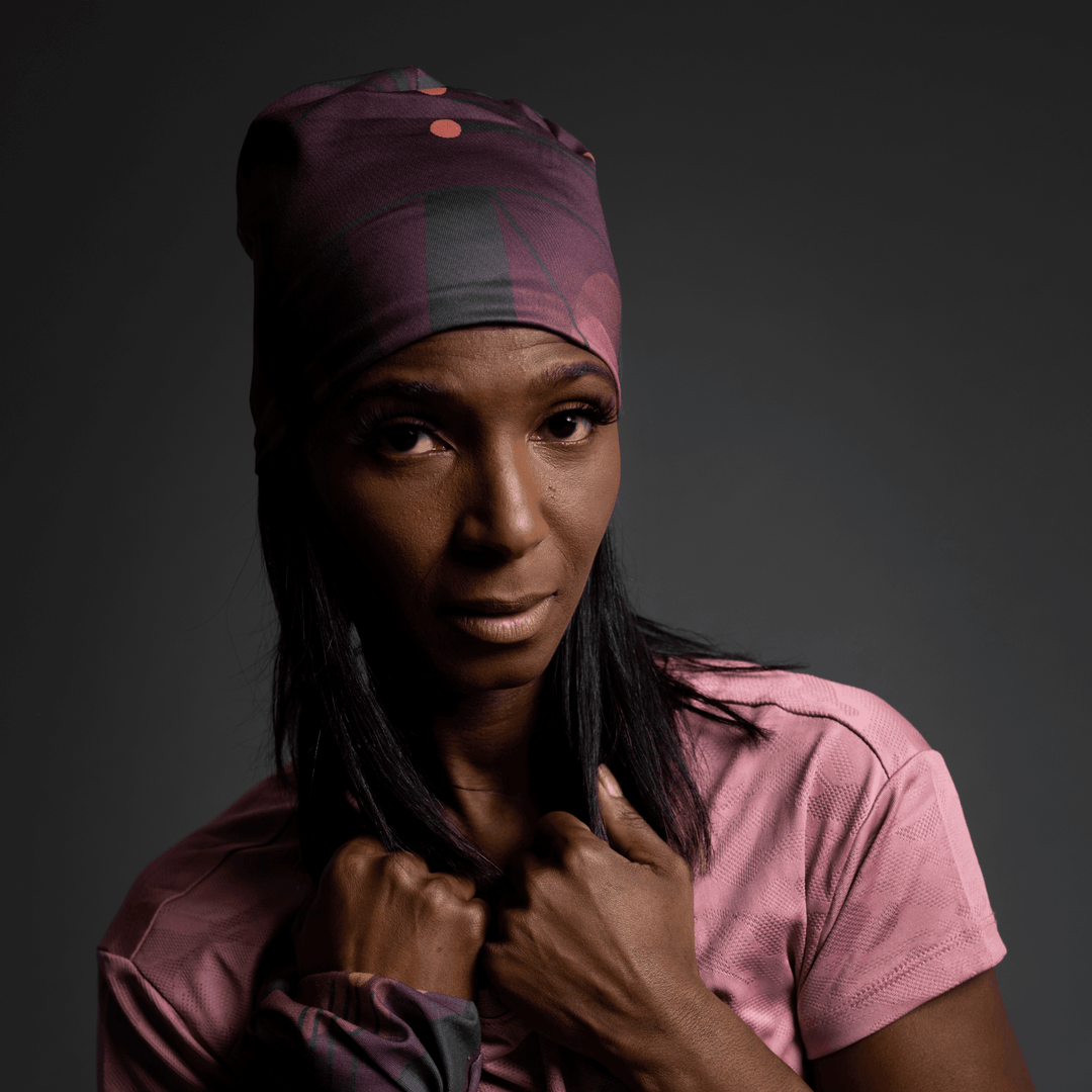 Femme ajustant sa tuque Motifs Géométriques Mauves, regardant ailleurs avec une expression sérieuse.