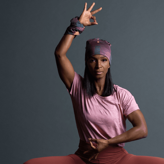 Femme portant une tuque Motifs Géométriques Mauves et un tube assorti, en position de yoga.