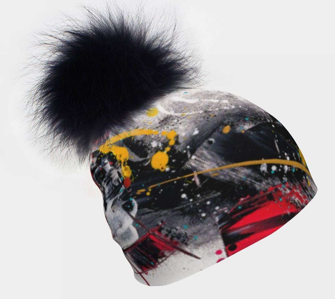 Tuque rouge et noire avec un gros pompon en fourrure noire sur fond blanc.