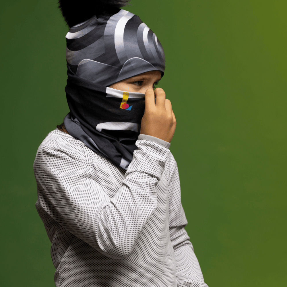Enfant portant une tuque et un cache-cou, remontant le cache-cou sur son visage.