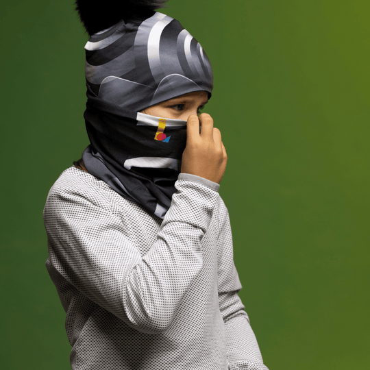 Enfant portant une tuque et un cache-cou, remontant le cache-cou sur son visage.