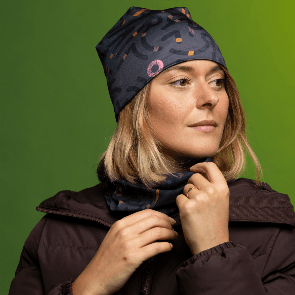 Femme portant une veste matelassée brun foncé, une tuque grise à motif abstrait et un cache-cou assorti.
