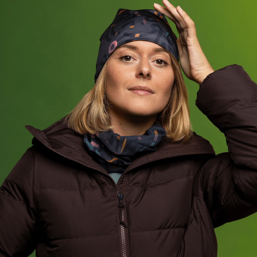 Femme portant une veste matelassée brun foncé, ajustant sa tuque grise à motif abstrait.