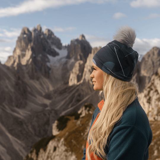 Femme portant la tuque bleu-vert regardant un paysage montagneux.