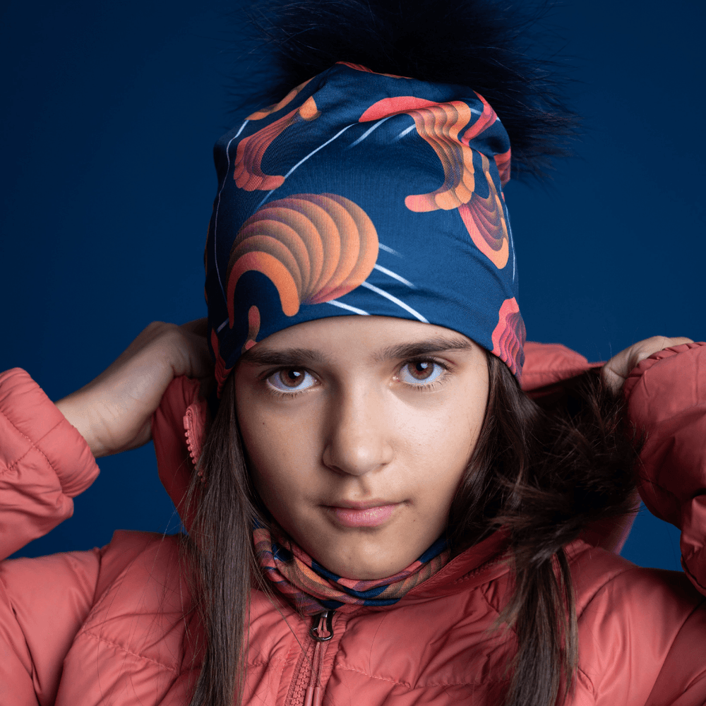 Jeune fille portant une veste d'hiver rose, la tuque marine avec motif abstrait et cache-cou assorti