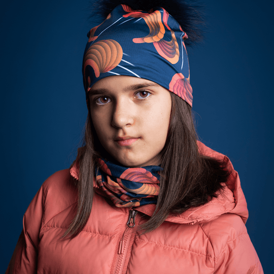 Jeune fille regardant devant elle, portant la tuque marine avec motif abstrait et cache-cou assorti