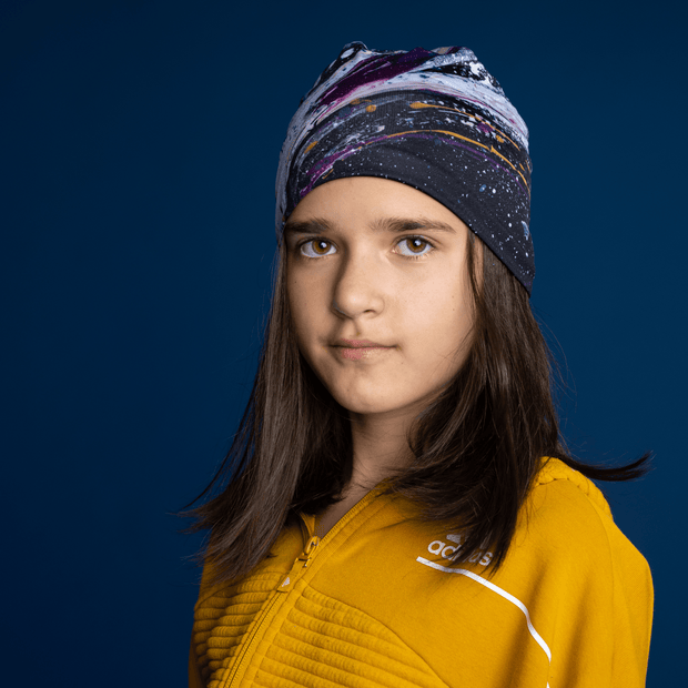 Proud young girl wearing the Lalita's Art Shop Abracadabra beanie model, with an abstract pattern on bamboo fabrics. Perfect hat for sports and outdoor activities, and suitable for the whole family