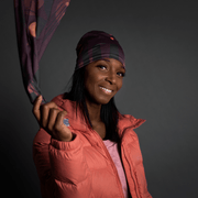 Young woman smiling and throwing the Geometrics purple multifunctional tube . Our multifunctional scarf designed by Valery Goulet can be worn in more than 10 different ways and will accompany you everywhere in your sports or outdoor activities. Lalita's Art Shop bandanas are perfect gifts for the whole family!