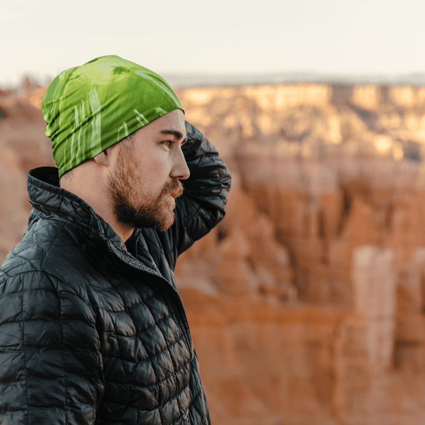 Profile view pf man in a canyon, wearing the Green light cap illustrated by André Martel. This cap is perfect for hiking, walking, and outdoor activities. 