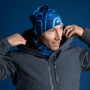 Man putting on his hood and wearing the mid-season beanie hat designed by Zaire. The bamboo beanie is in blue tones with geometric shapes.
