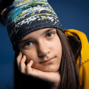 Young girl from the front wearing the Meduse hat designed by Megane Fortin. This beanie is black with green, blue, white and orange abstract patterns
