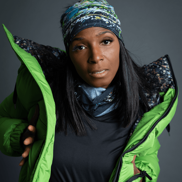 Sporty woman wearing a green winter coat and the Meduse beanie designed by Mégane Fortin. This beanie is black with an abstract design and a detachable pom pom