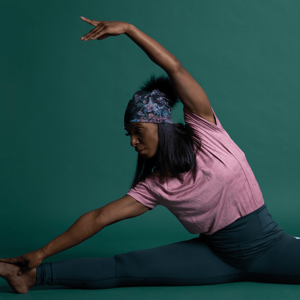 Woman doing streching with beautiful beanie hat with flowers design and black Pompon. The yoga bamboo beanie is design by Claire Anghinolphi