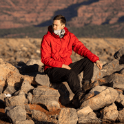 Man sitting on rocks, looking far away wearing multifunctional tube Lalita’s Art Shop with fleece.  This headbands illsutrated by Catherine Parent are made of recycked fabrics and have an addition of 20 cm of Fleece to keep you warm in winter. 