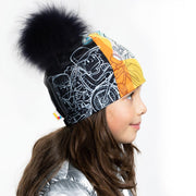 Left Side view of girl wearing Black and white doodle pattern toque with black pompon.
