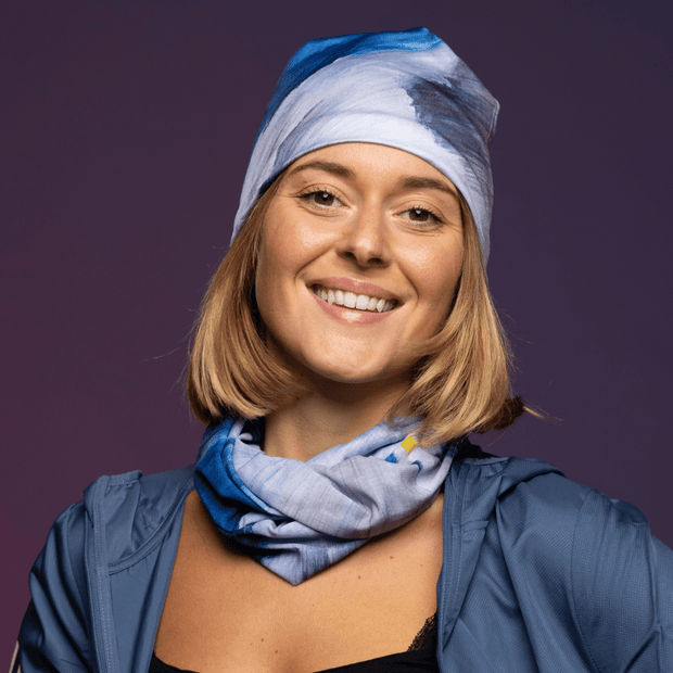 Woman wearing the Blue and Gray Golden Sea multifunctional tube with assorted bamboo beanie by Elise Charette for Lalita's Art Shop