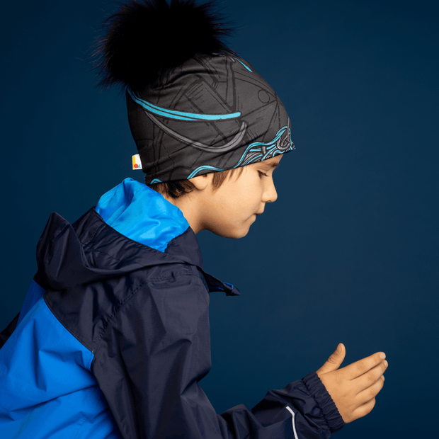 Young boy running side view wearing the Robocat 4seasons beanie designed by André Martel. The bamboo sports beanie hat has a black pompom. 